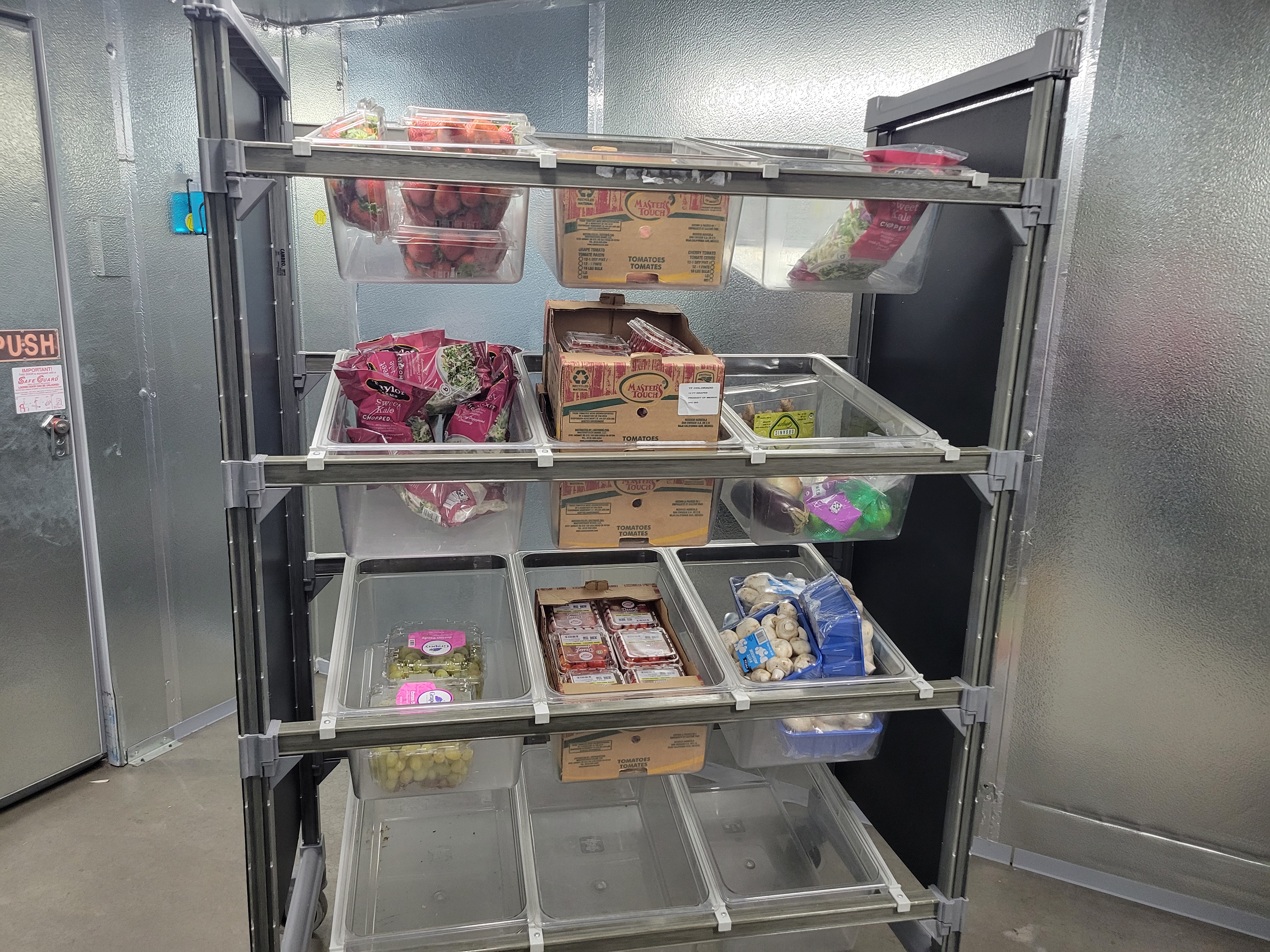 Calmshell cases, bags, boxes, and container of produce in the tubs of a display case.
